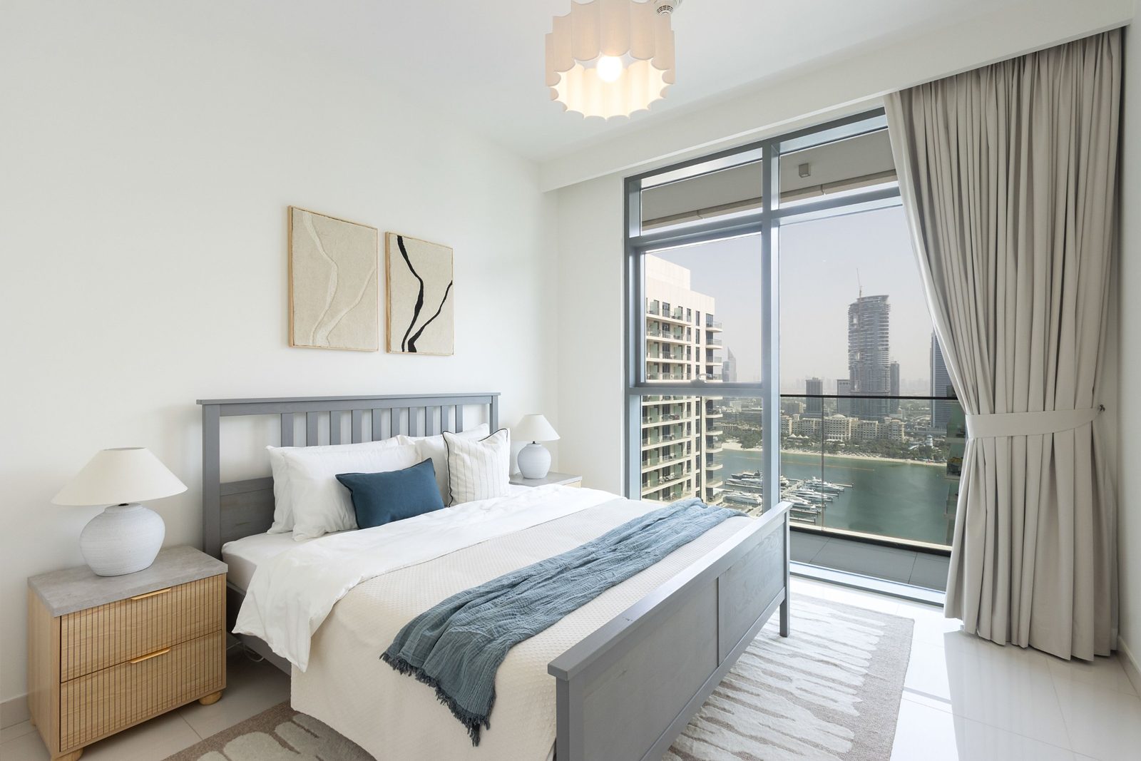 Guest bedroom with the kept grey bed, new fluted bedsides, two tufted artworks and the Marina view
