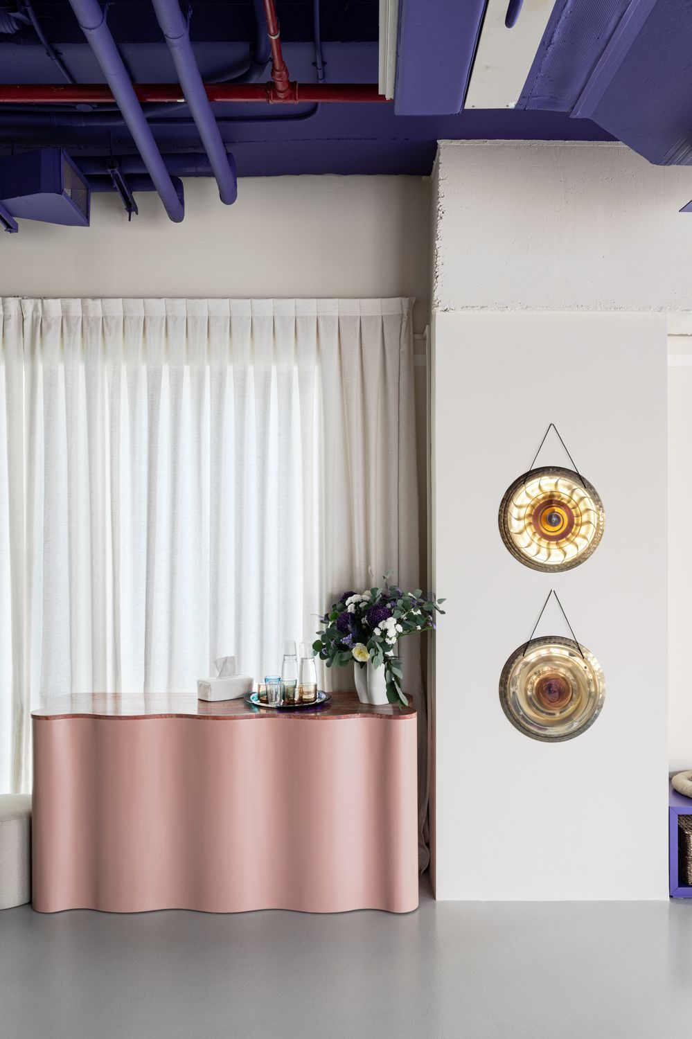Reception with wavy blush console and gongs on the wall