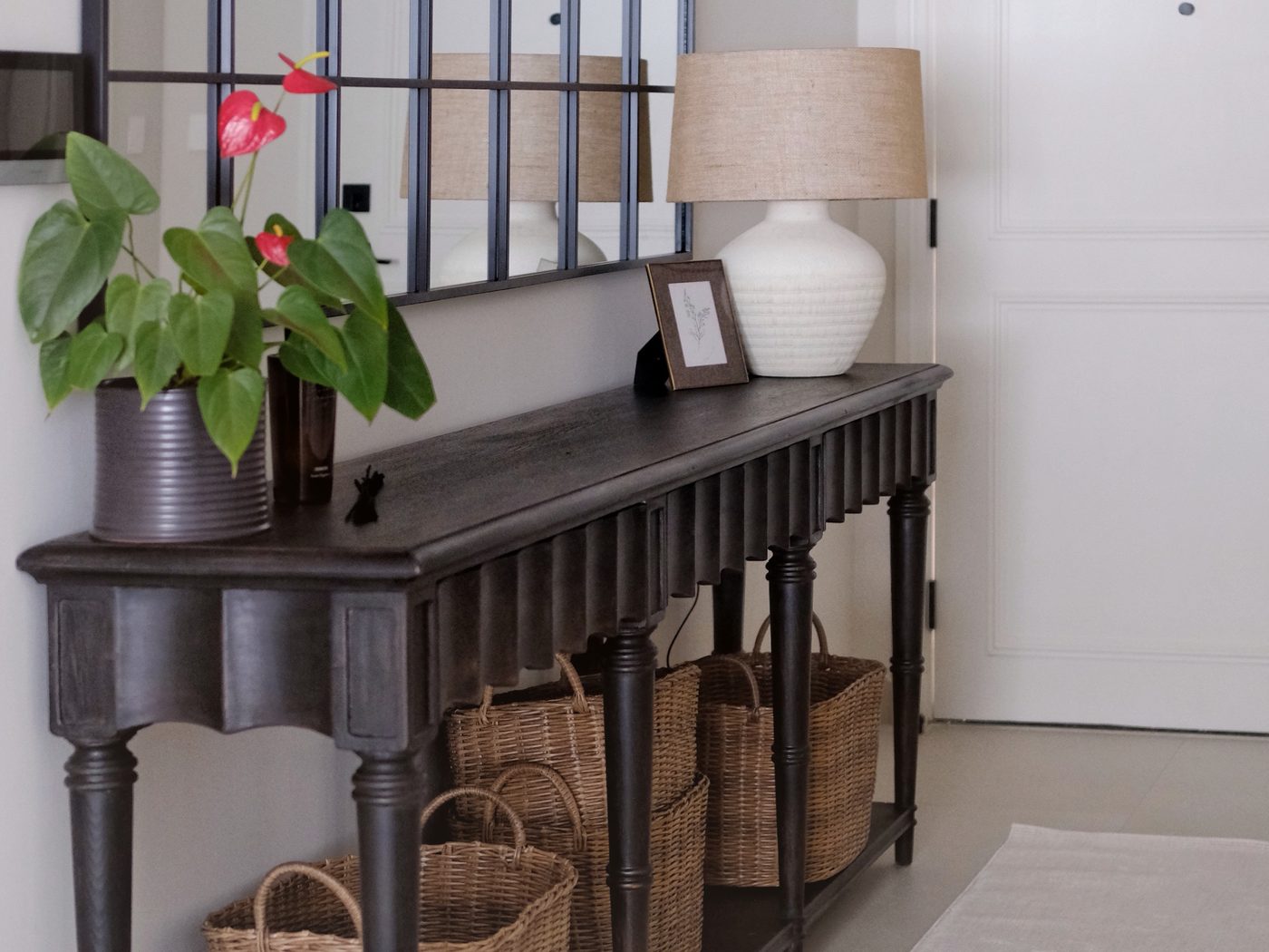 Entryway — dark scalloped console with ceramic lamp, grid mirror and wicker baskets